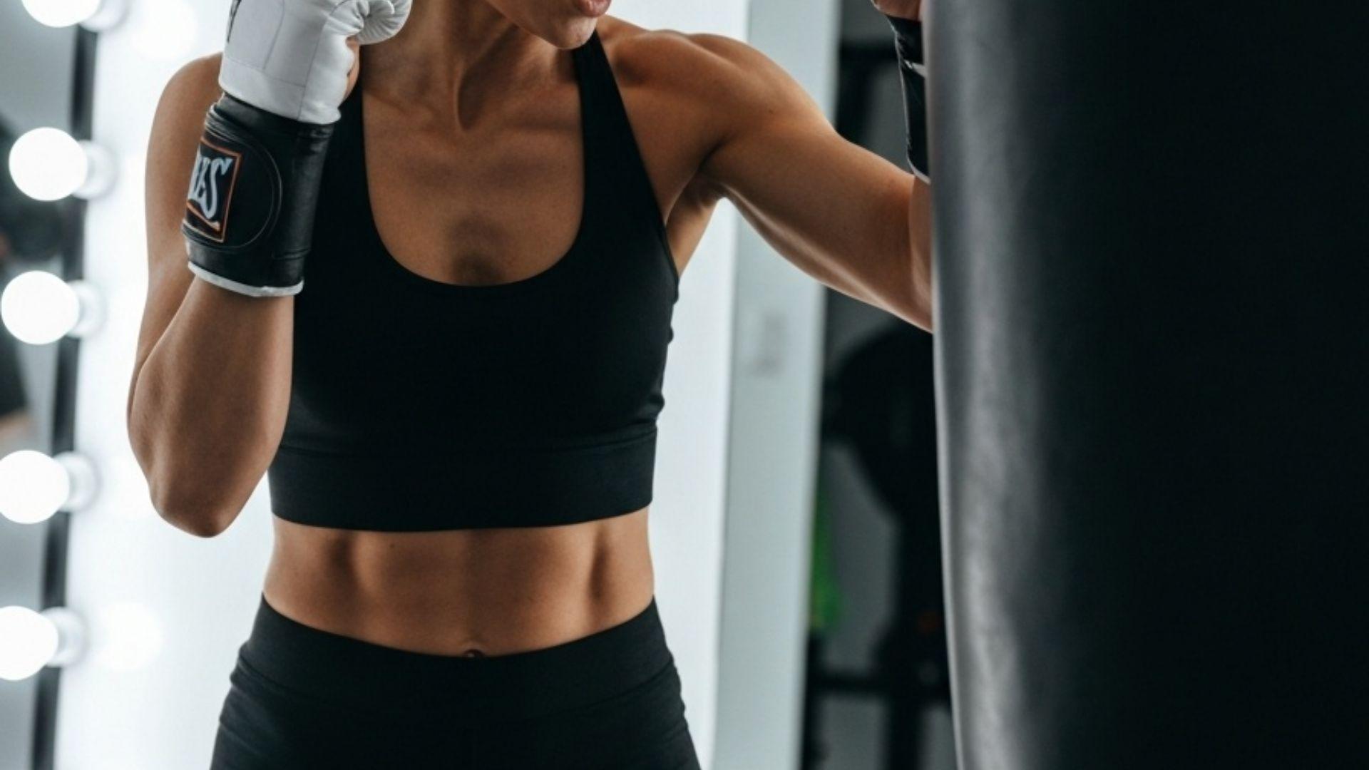 Kvinne slår på boksesekk i hjemmegym