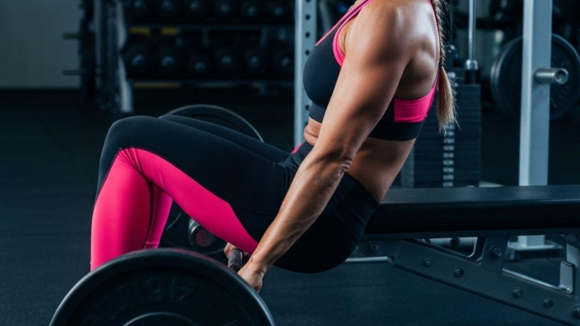 Person som utfører hip thrust med vektstang mot treningsbenk