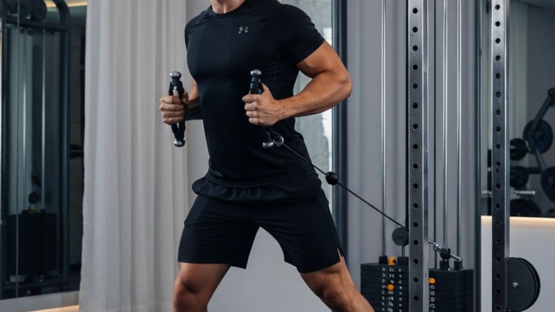 Mann trener kabeløvelser på functional trainer i hjemmegym