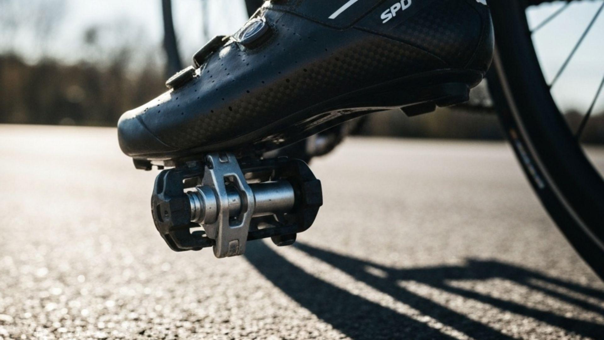 Nærbilde av en syklist som klikker sykkelskoen fast i SPD-pedalen — detaljert bilde av klossmekanismen og den stive karbonsålen