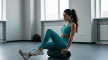 Kvinne bruker foam roller for restitusjon i treningsstudio