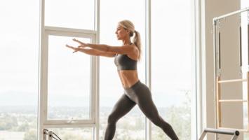 Kvinne trener pilates på reformer maskin i lyst studio