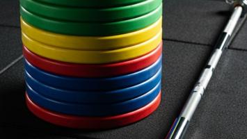 Sortert sett med fargede olympiske bumper plates vektskiver i et treningsstudio